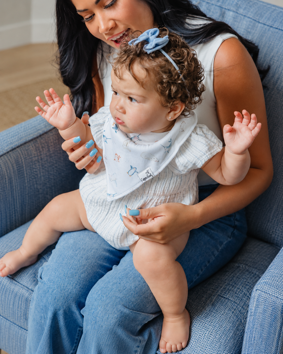 Baby wearing a Copper Pearl Arctic Wonder bandana bib with Arctic animal prints while sitting on her mother’s lap.
