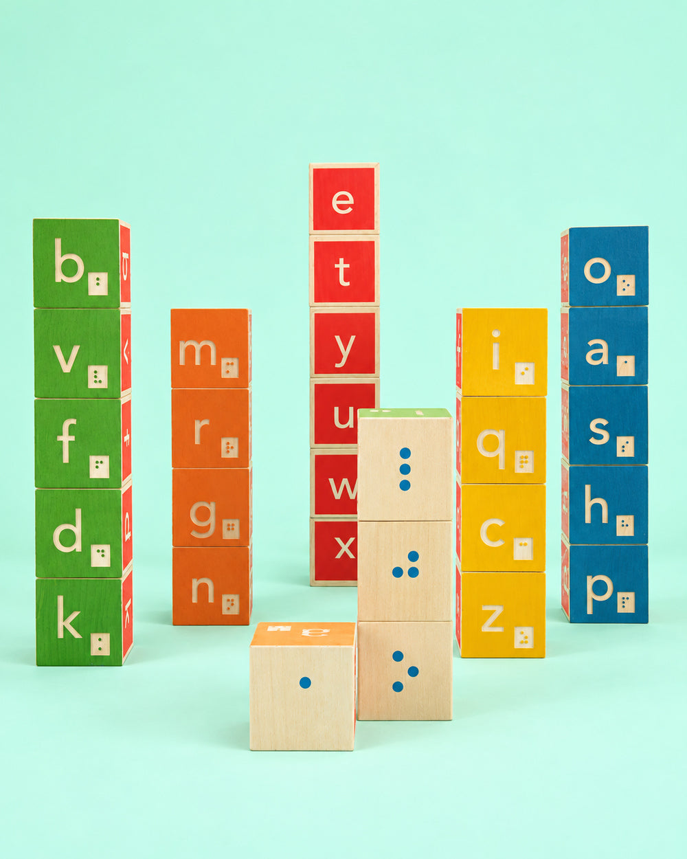 Colourful Uncle Goose Braille alphabet wooden blocks arranged in towers against a mint background