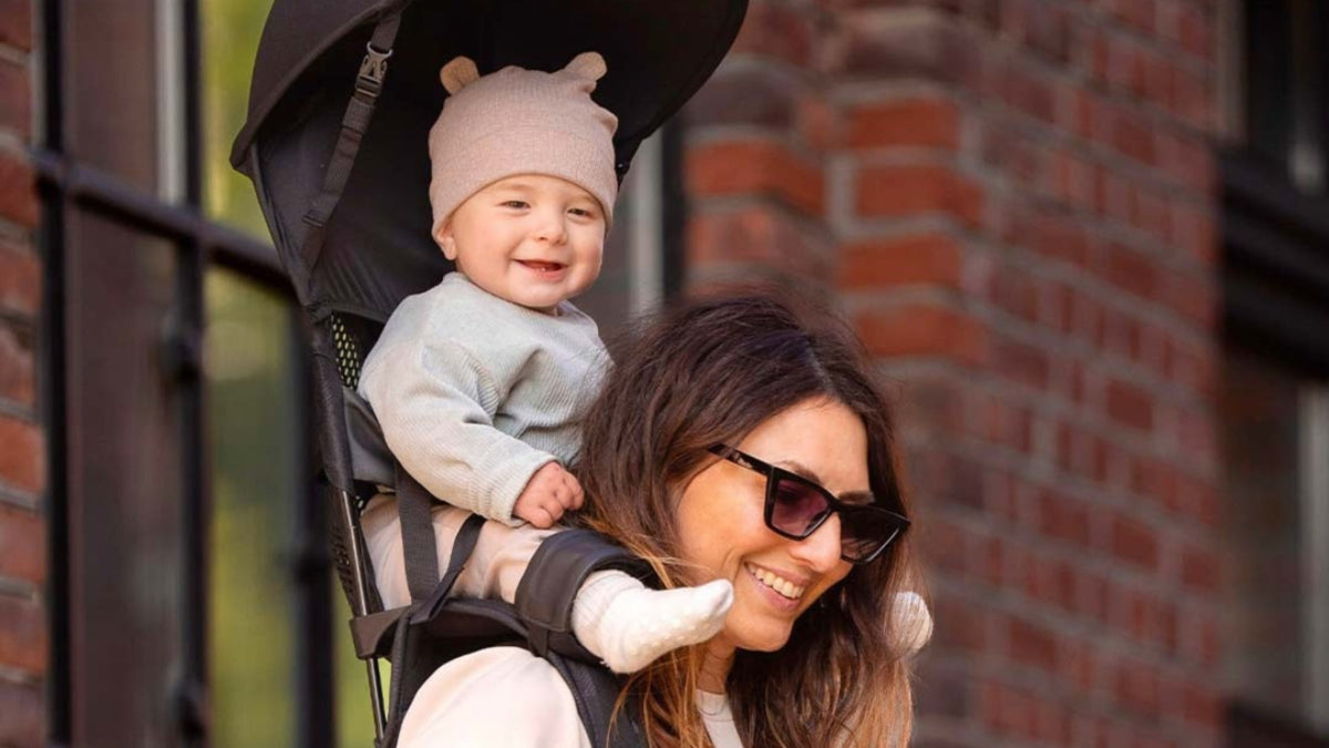 Singaporean mother showing baby carrier safety with newborn held high and close in an ergonomic carrier