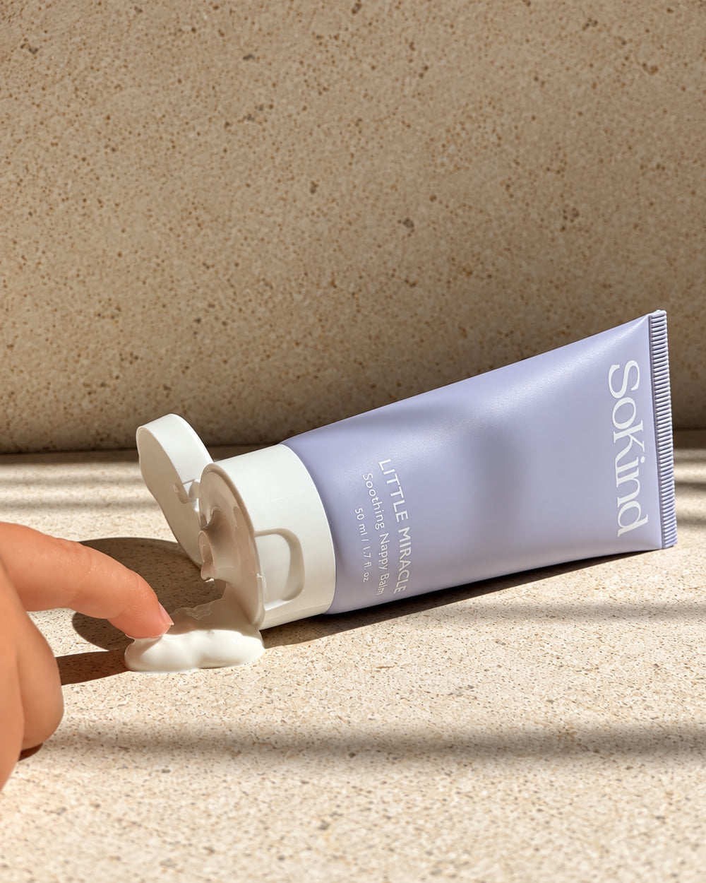 SoKind Little Miracle Soothing Nappy Balm with open cap and a dab of cream