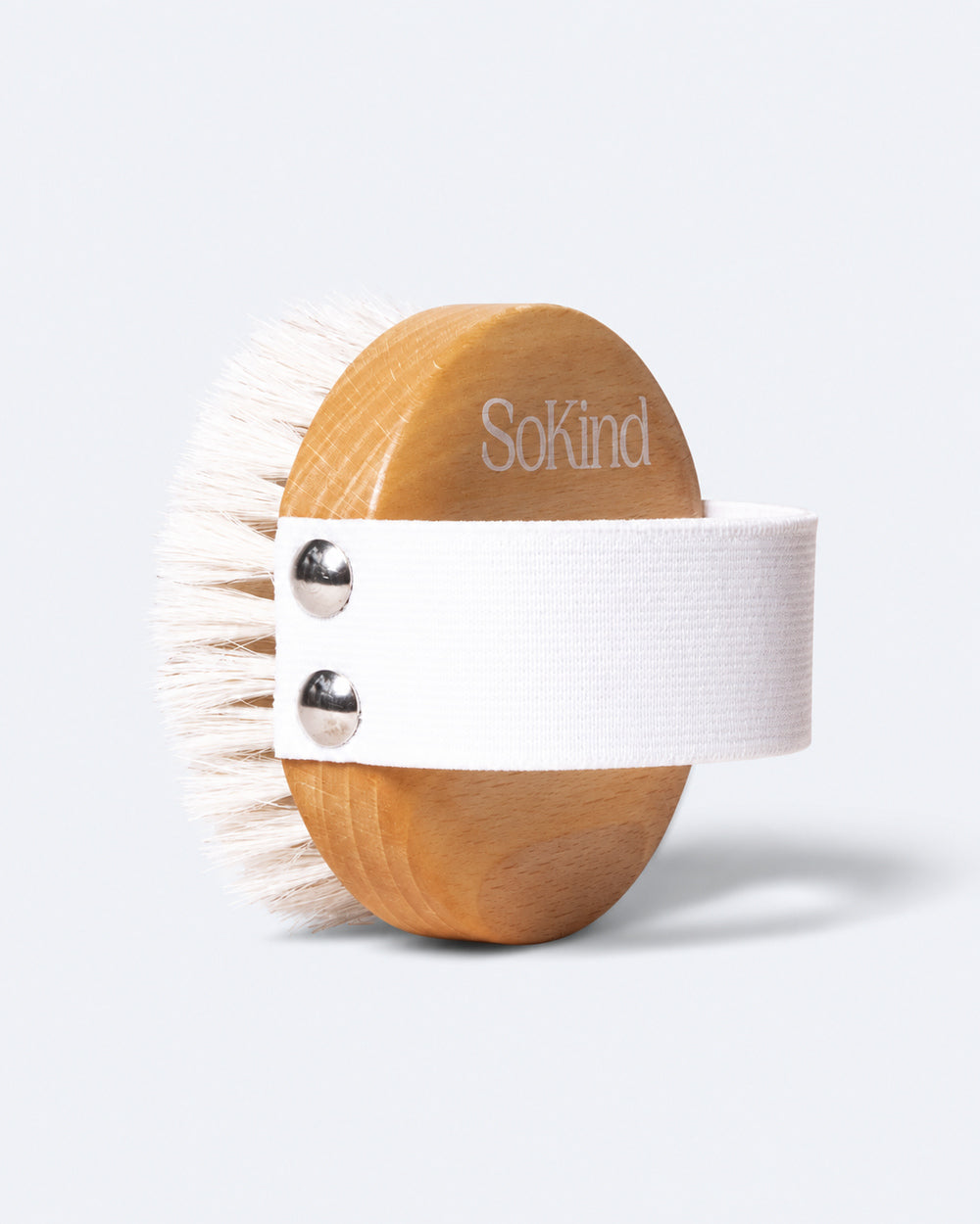SoKind wooden body brush with white hand strap used for dry brushing a leg